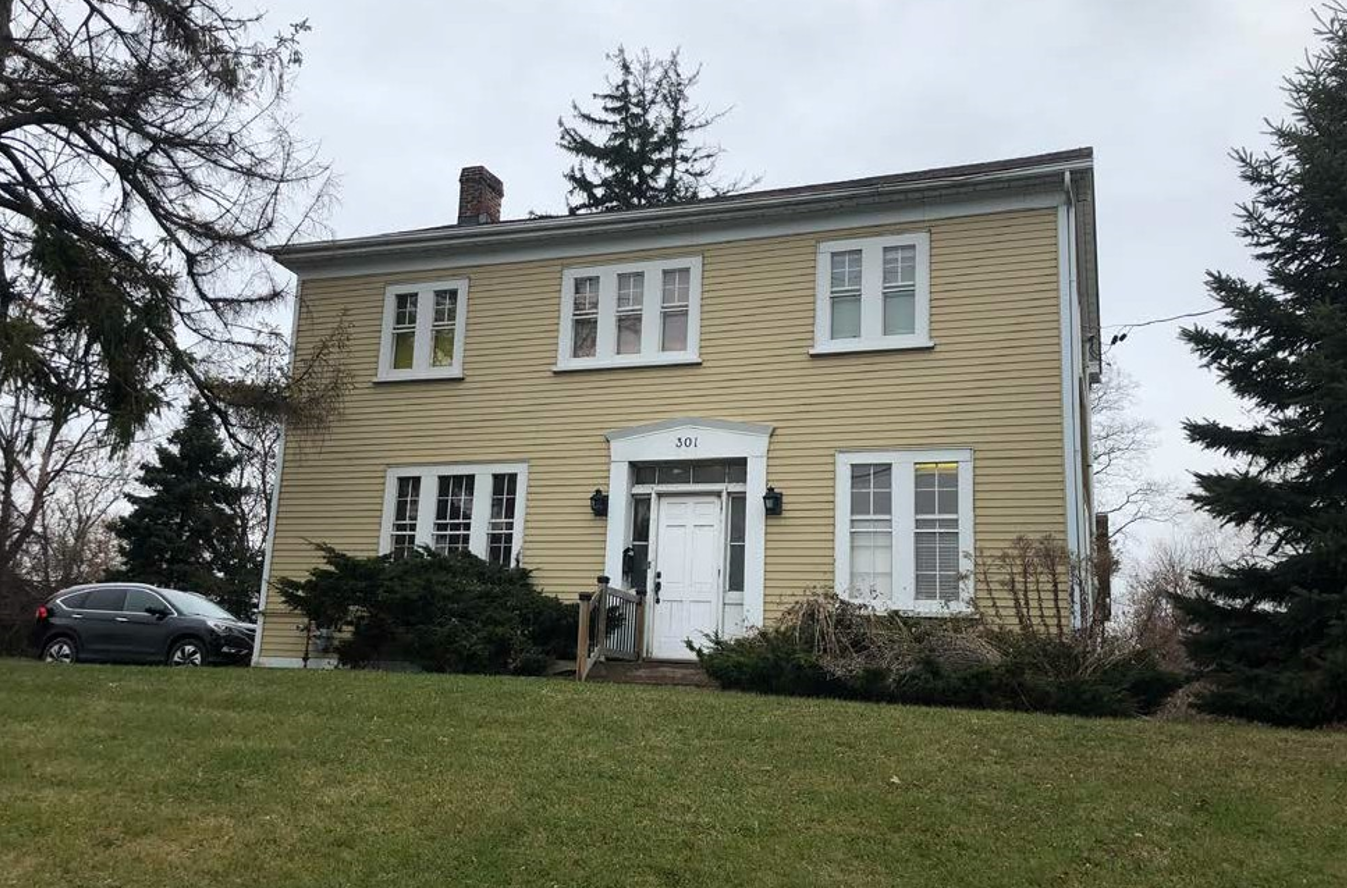 The front of 301 Kingston Rd in 2019: A pale yellow panelled building with white window frames